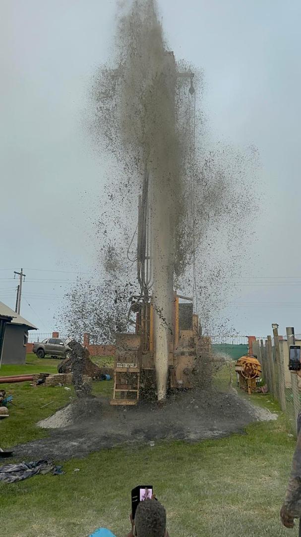 Borehole strike — drilling debris erupting from the ground